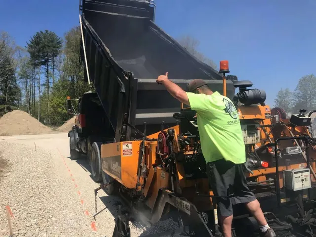 Asphalt paver with worker pointing to road surface