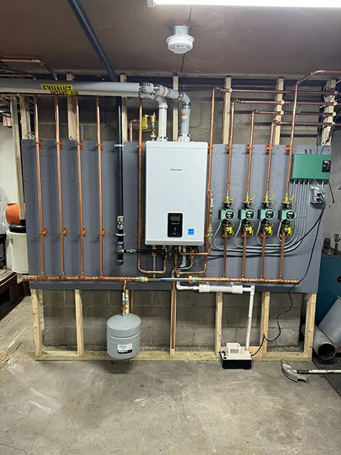 A wall-mounted multi-unit furnace system with organized copper plumbing pipes, valves, and control pumps in a basement setting.