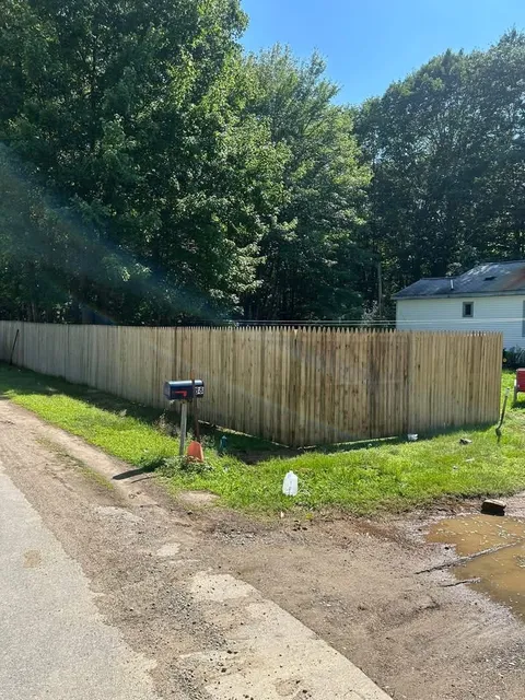 Wood stockade fence installed along a roadside property line