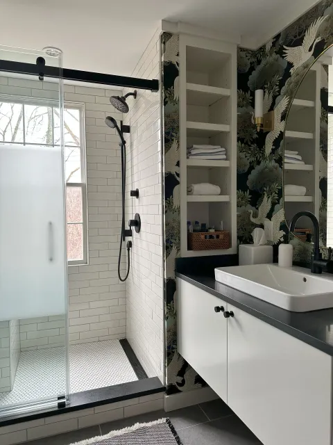 A bathroom with a sink , shower , and mirror.