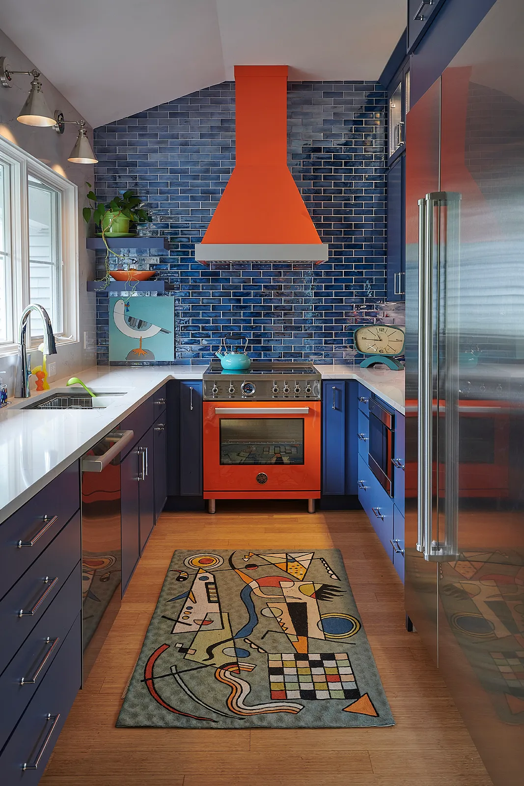 A deep Italian orange Bertazzoni range sets the tone, its warmth and personality immediately commanding the room. A custom hood mirrors that presence overhead, grounding the space in quiet sophistication.