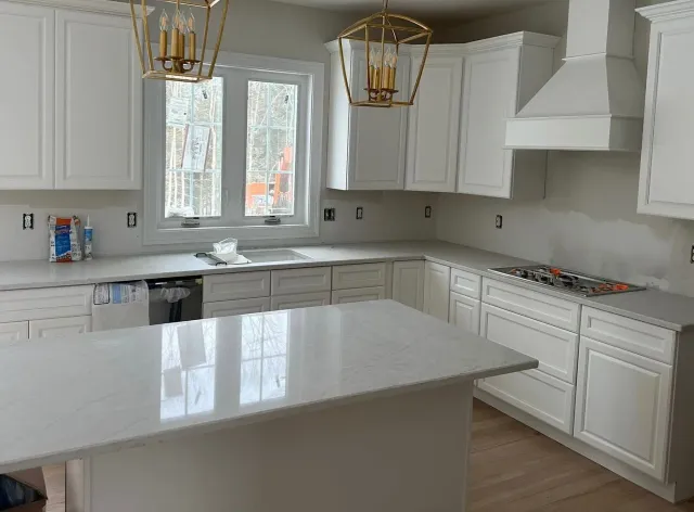 A kitchen with white cabinets and a large island in the middle.