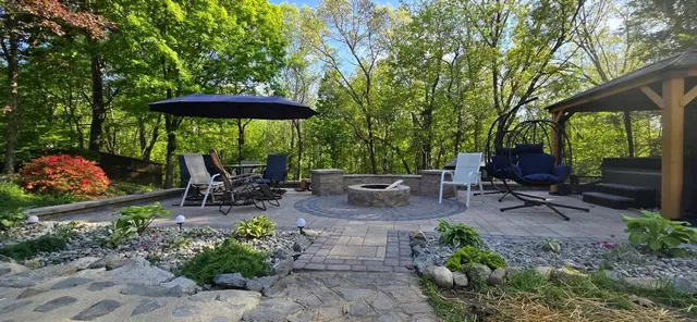 Backyard patio with pergola, fire pit, plantings and stone paths near Concord, NH