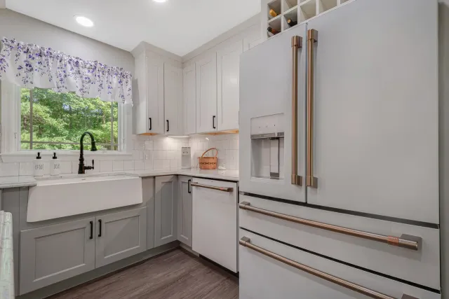 A kitchen with white cabinets, a white refrigerator, a sink, and a window
