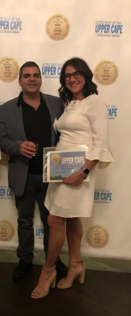 A man and a woman are standing next to each other in front of a wall.