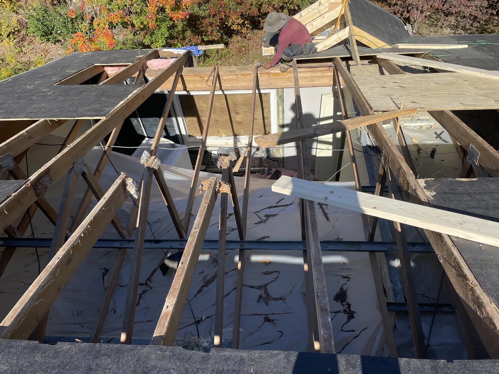 Roof stripped down to the rafters during a tear-off with a Storm King Roofing worker on the ridge in Avon, MA