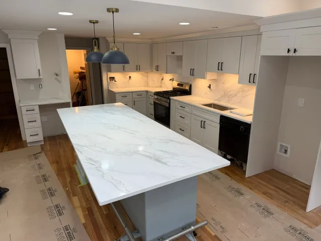 Bright kitchen with white cabinets, marble island, and blue pendant lights