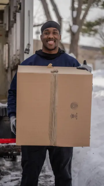 Cyan Movers Professional mover carrying a moving box during a residential relocation in Connecticut