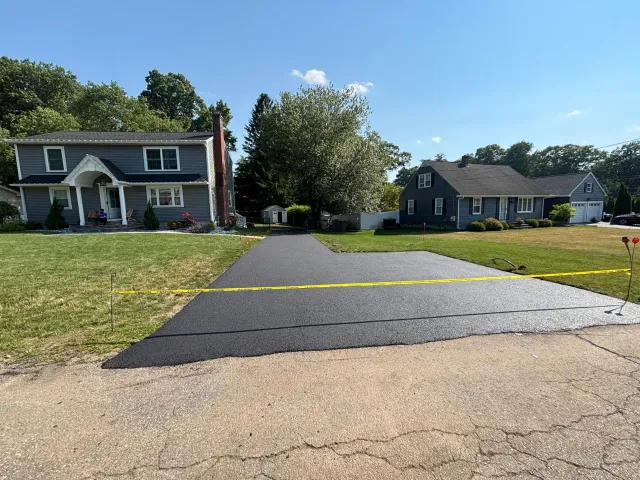 Asphalt paving crew installing hot mix on a Massachusetts driveway