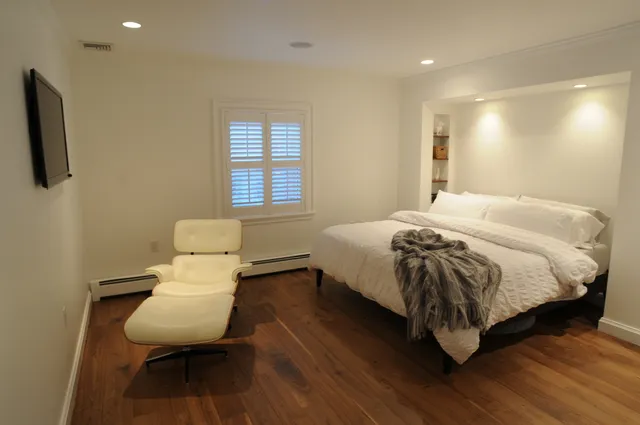 Finished bedroom with wide-plank walnut floor and built-in niche