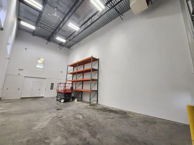 The fully completed commercial drywall installation featuring a smoothly finished and painted white warehouse partition.