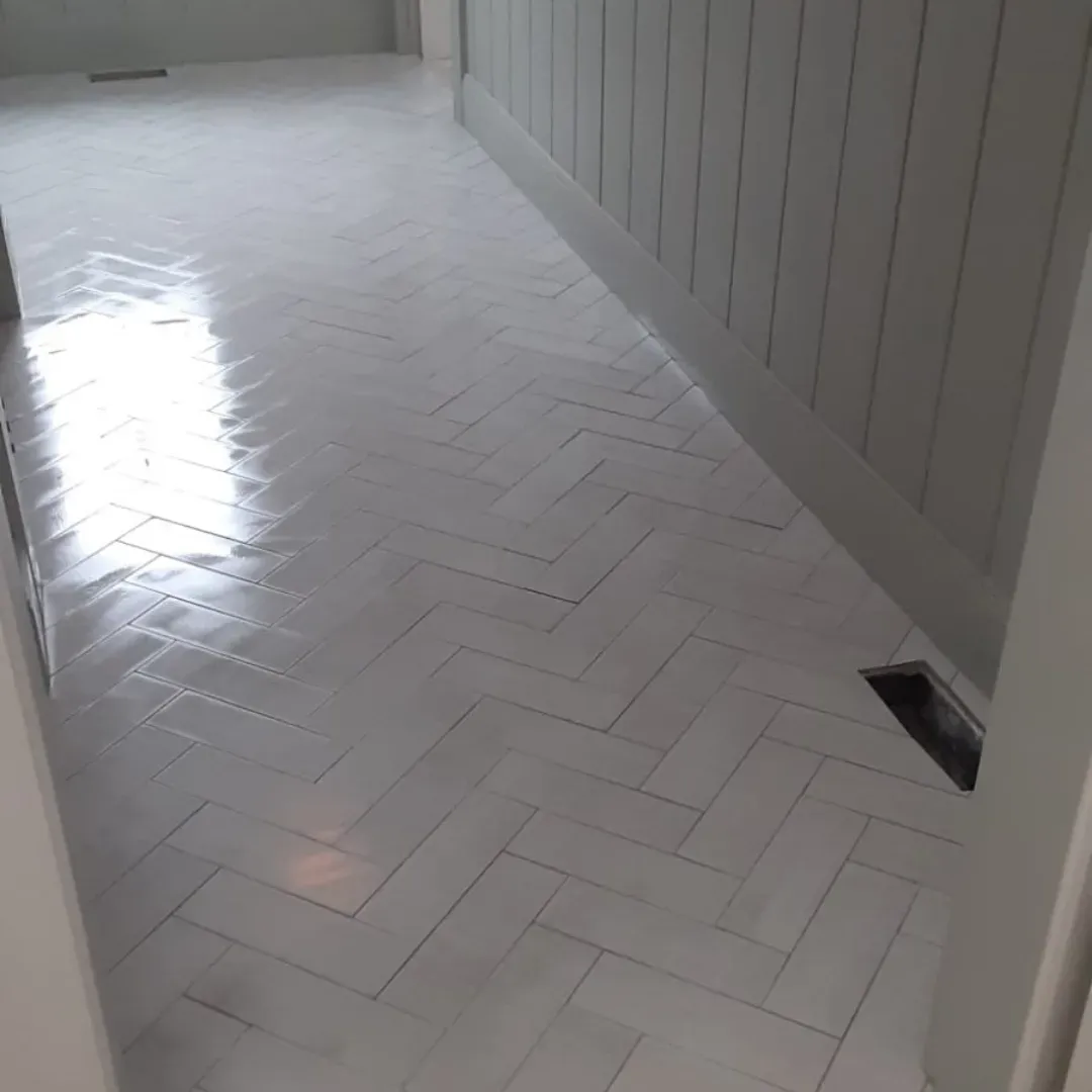 Glossy white herringbone tile floor along shiplap wall by Link Services Pro in Westborough, MA