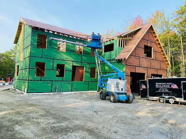 A large house is being built with a crane in front of it.