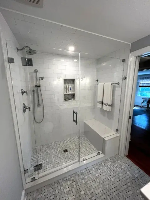Spacious walk-in shower with glass enclosure and white tile walls.