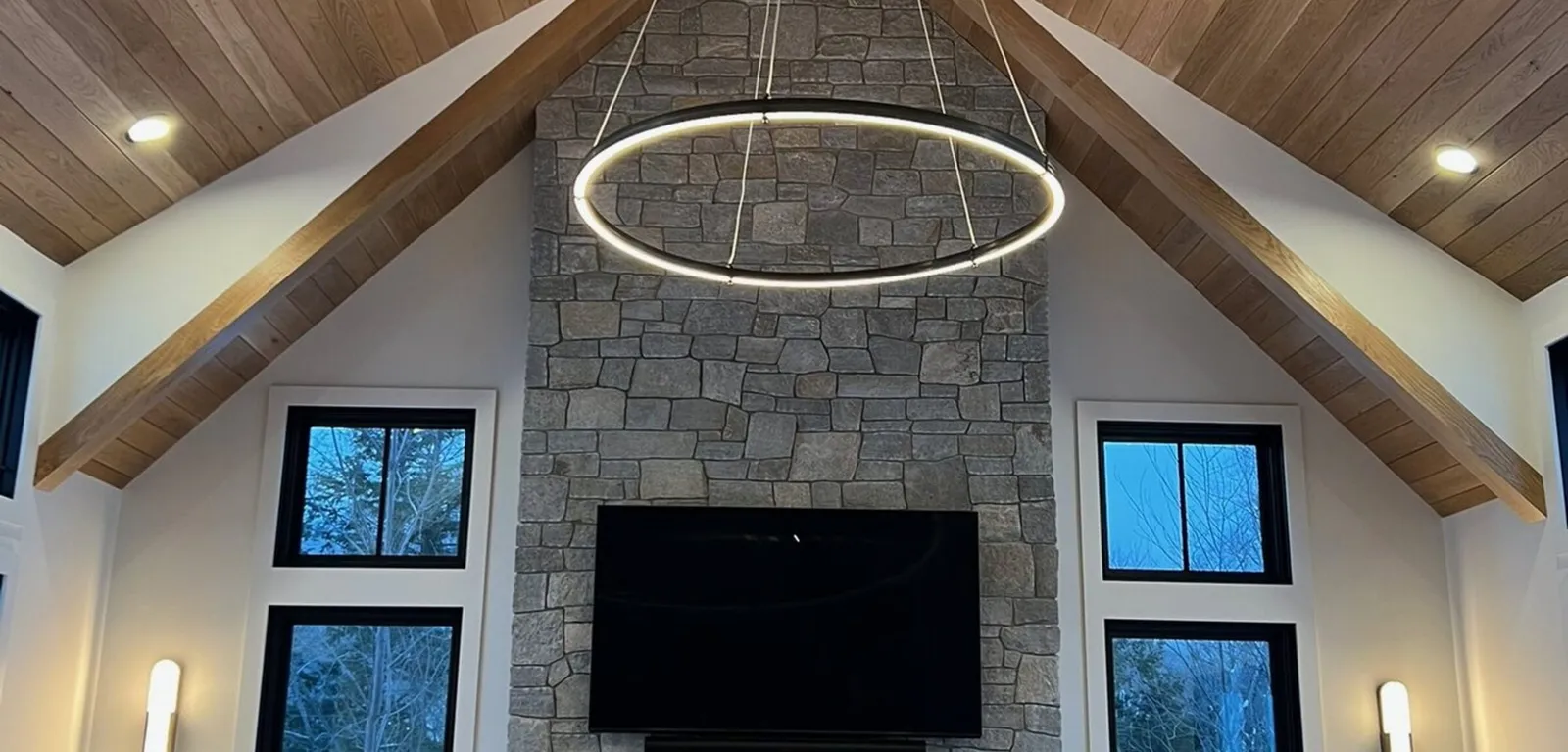 Great room with exposed beams, a wood ceiling and a full height stone fireplace