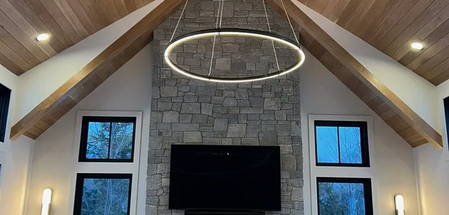 Great room with exposed beams, a wood ceiling and a full height stone fireplace