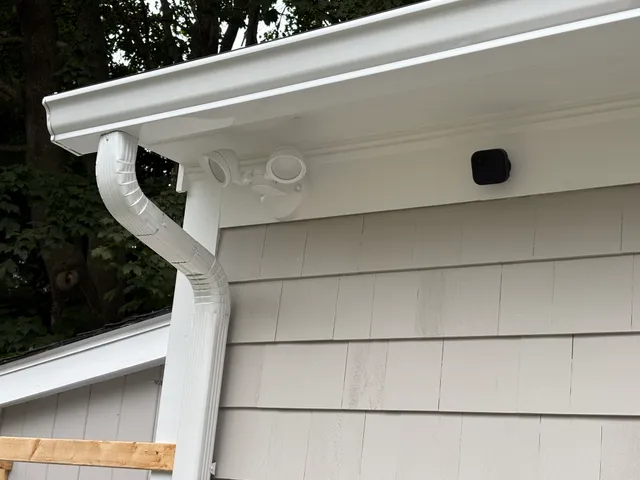 White gutter corner with downspout and security light