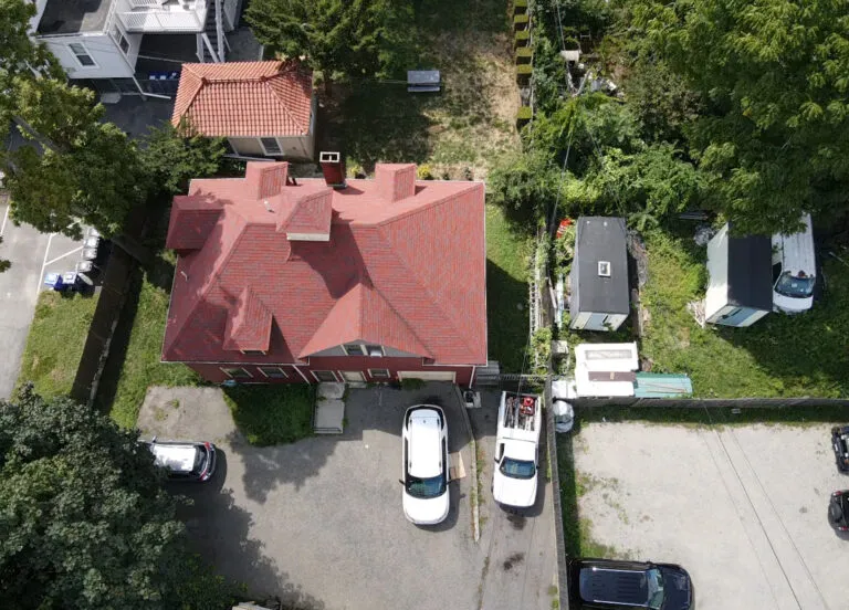 Aerial drone view of a red roofing system on a residential property during roof inspection in Boston, MA.