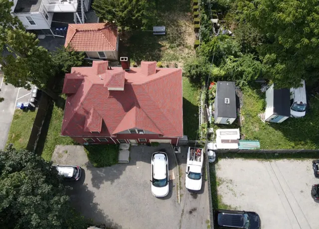 Aerial drone view of a red roofing system on a residential property during roof inspection in Boston, MA.