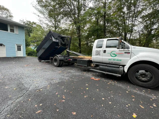 Truck unloading dumpster at residential property