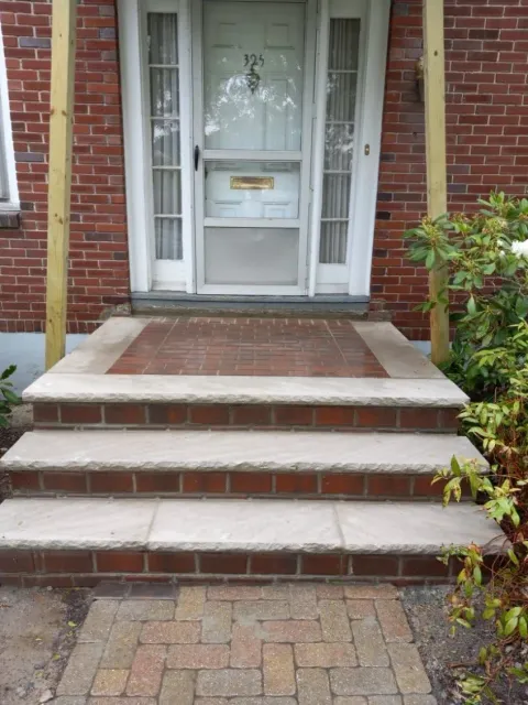 Brick steps leading to a front door with a screen. Wooden posts flank the door.