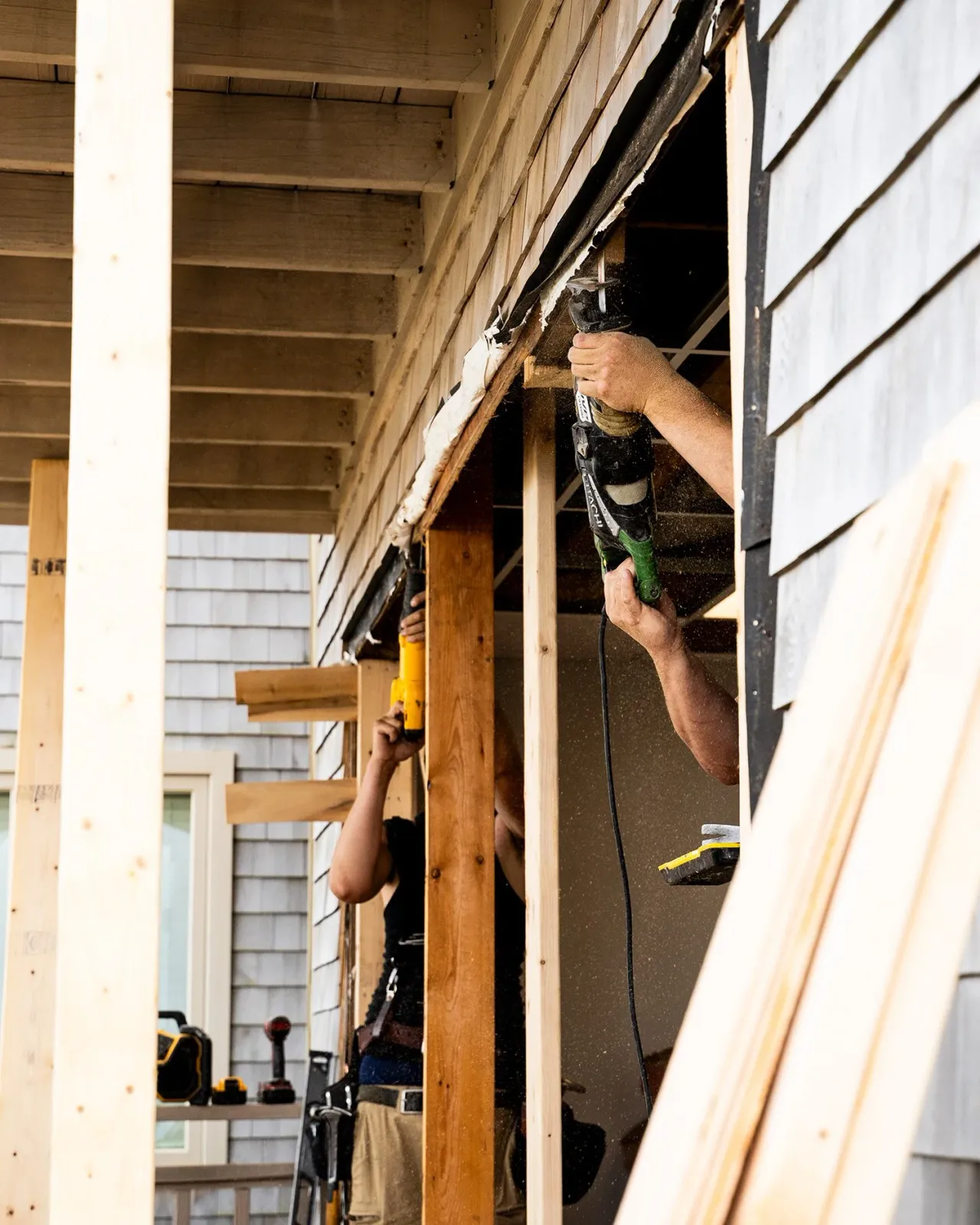 Workers using power tools to frame the interior of a house during construction.