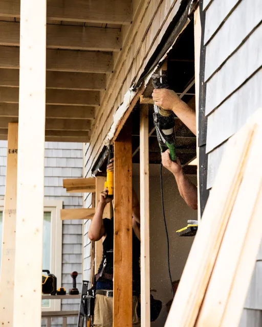 Workers using power tools to frame the interior of a house during construction.