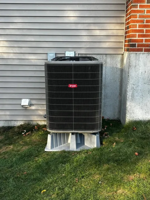 Bryant air conditioning condenser on a composite pad beside a brick chimney
