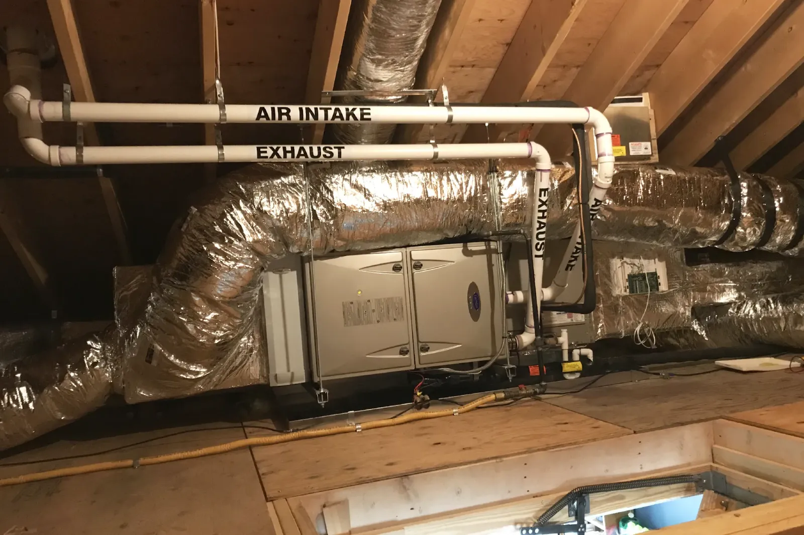 A Carrier heating and air conditioning system professionally installed in a Cape Cod home attic by Robies, showcasing high efficiency HVAC design and quality ductwork