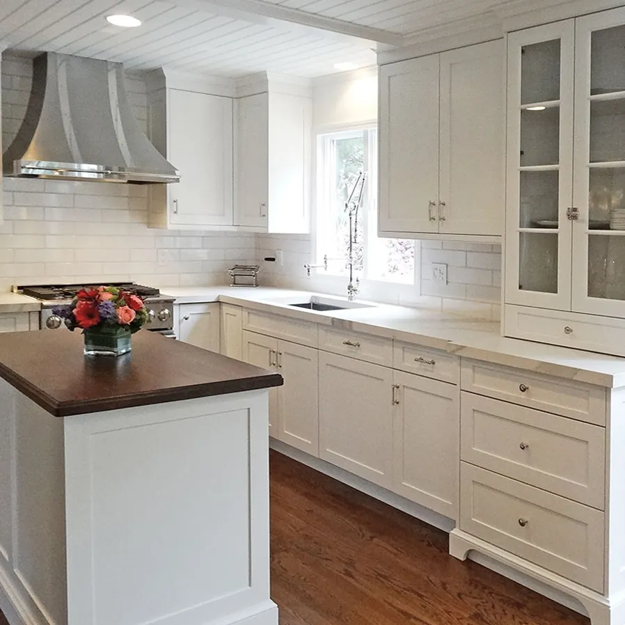 Modern kitchen with white cabinets, white subway tile backsplash, and dark wood island countertop.