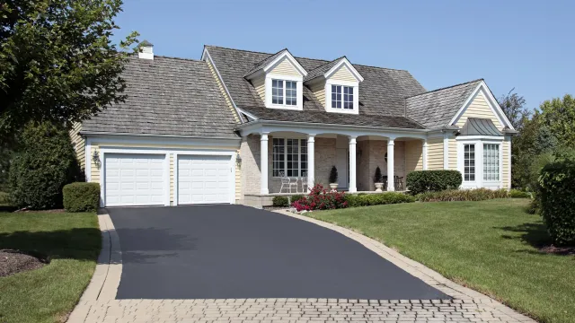 A two-story house with a double garage, covered porch, and manicured lawn.