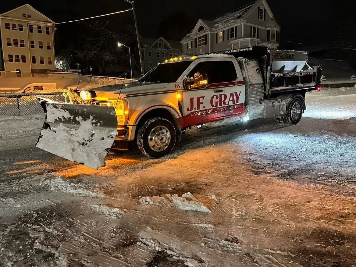 Snow plow truck clearing a snowy street at night. The truck has the