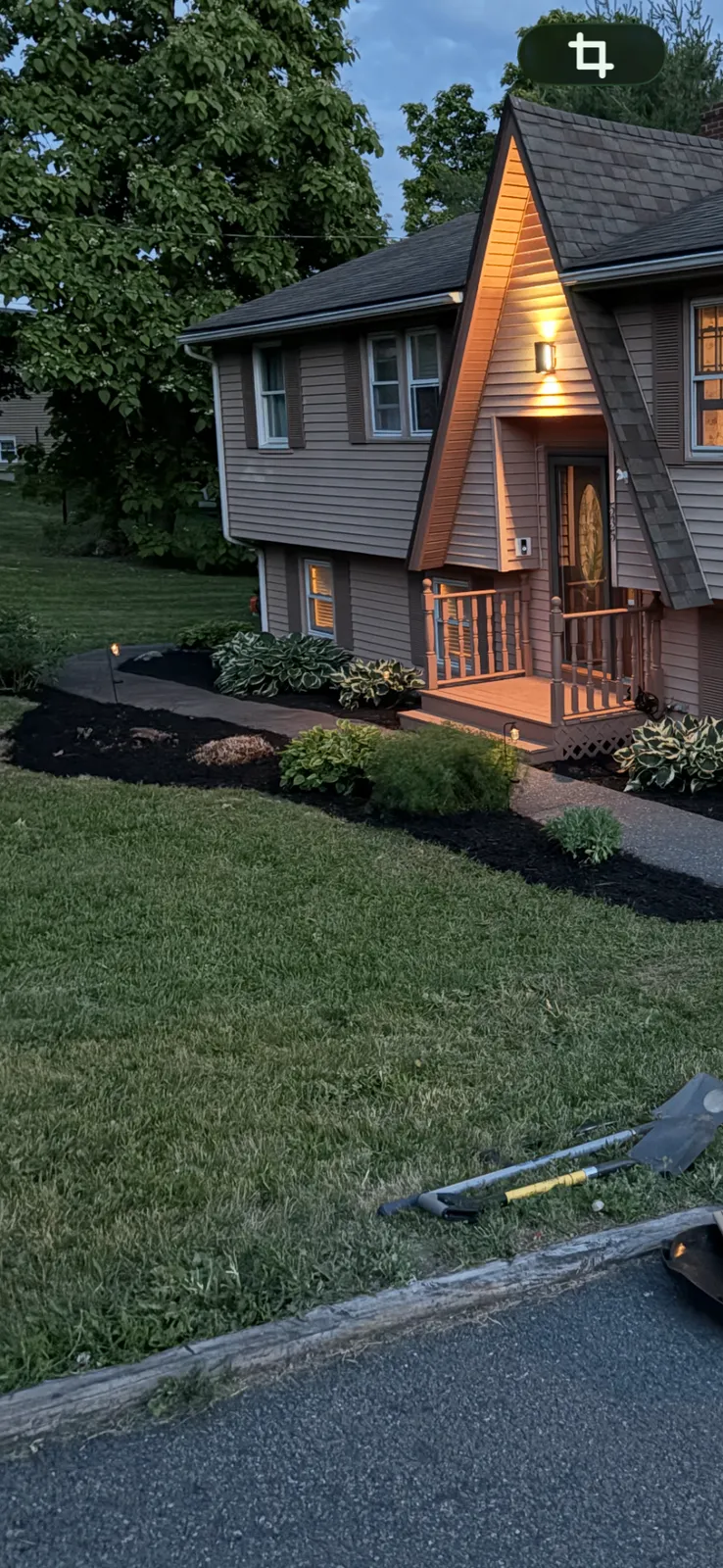 Landscaped home at dusk with a manicured lawn and fresh mulch beds