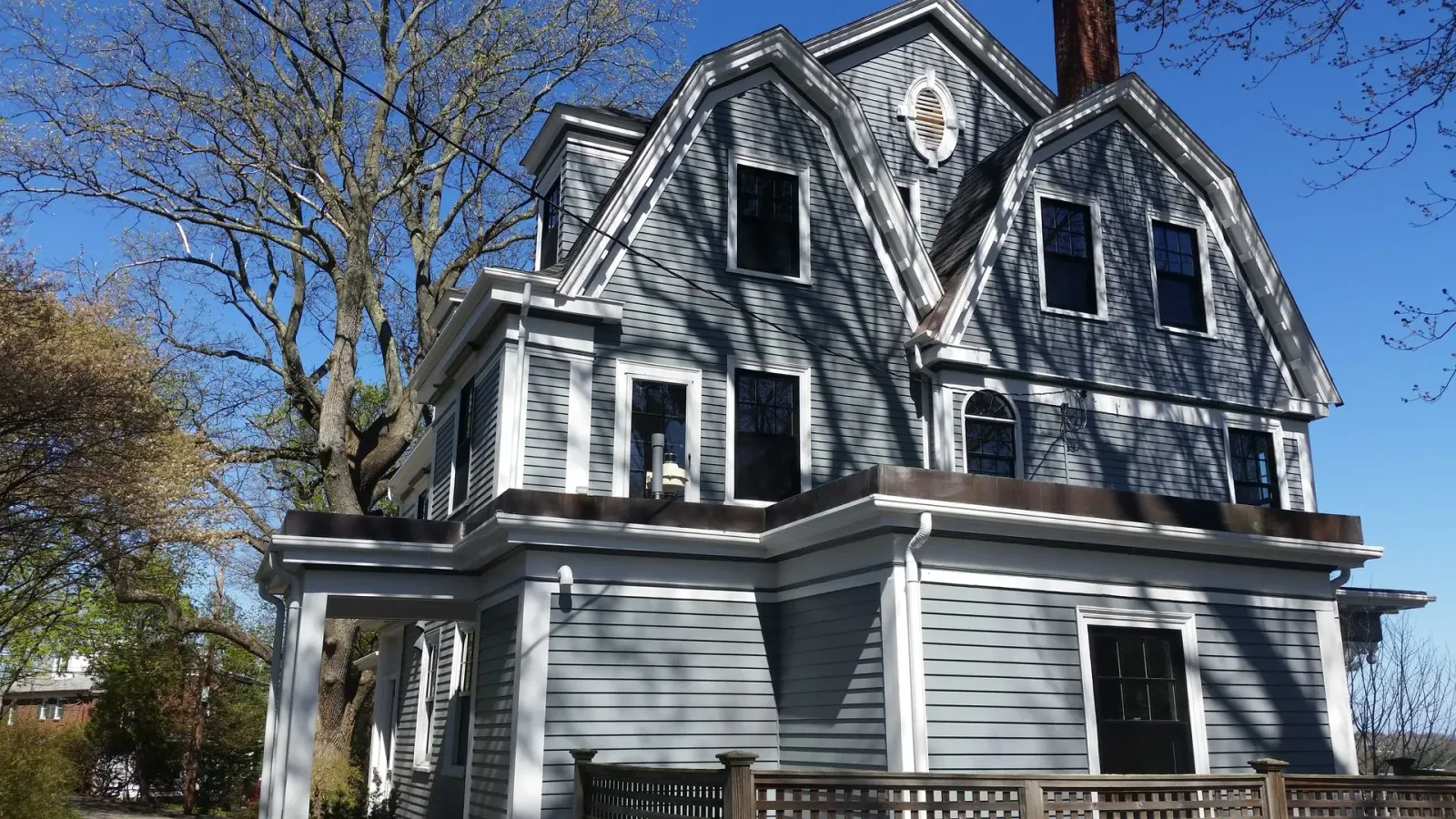 Gray Victorian house with multiple gables and windows, set against a blue sky.