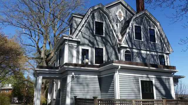 Gray Victorian house with multiple gables and windows, set against a blue sky.