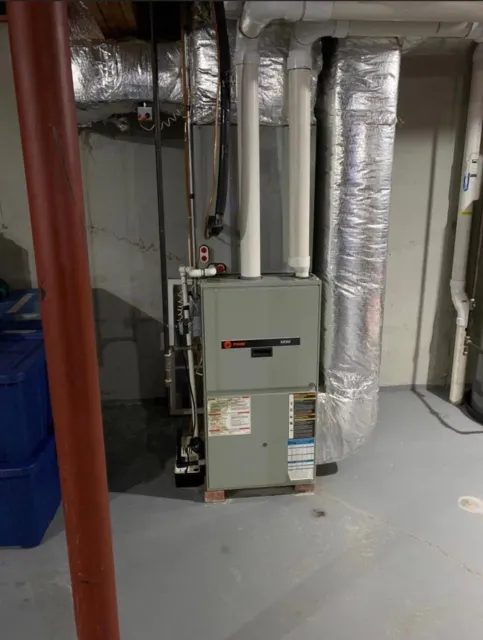 Basement utility room with furnace, ductwork, and red support pipe on a gray floor.