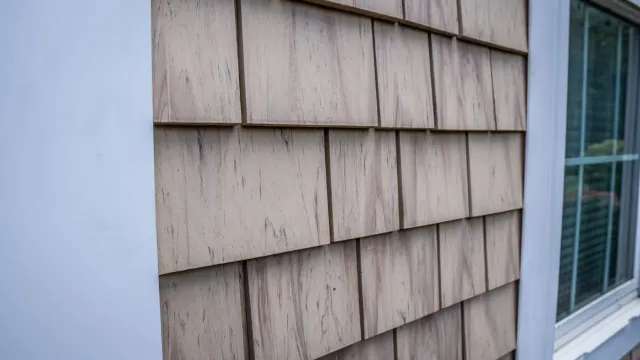 A close up of a wooden siding on a house with a window.
