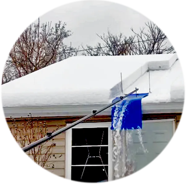 Snow is piled on a roof and the snow is removed by a pole and shovel