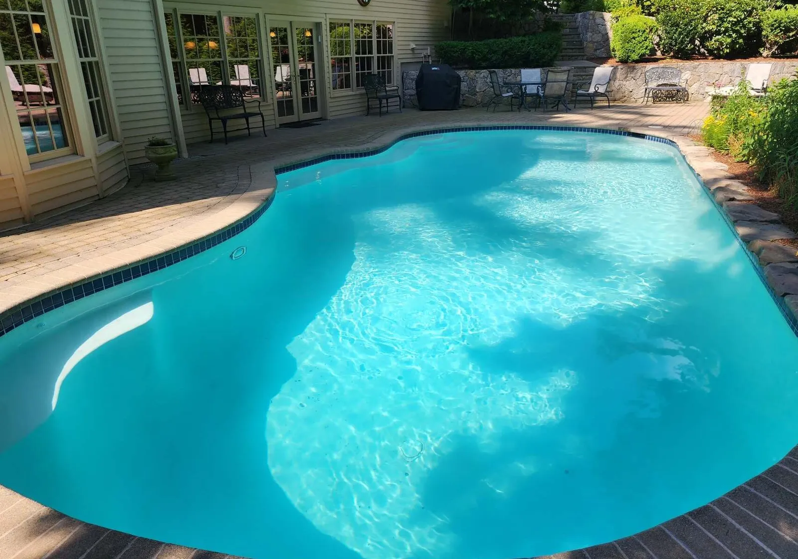 A pool with blue water and brick steps.