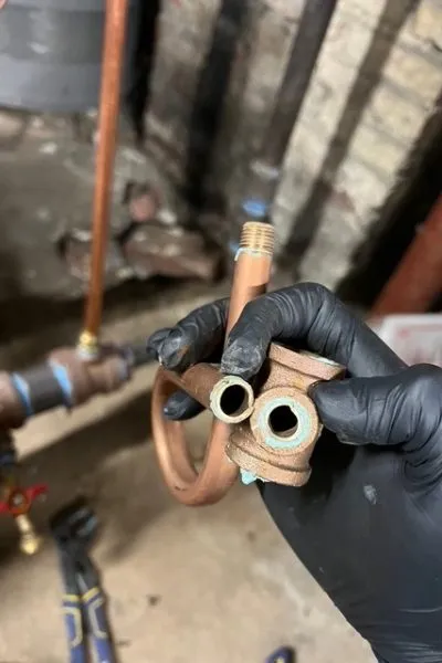 Gloved hand holding copper plumbing fitting