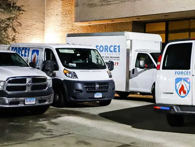Force1 restoration service vehicles parked outside building.