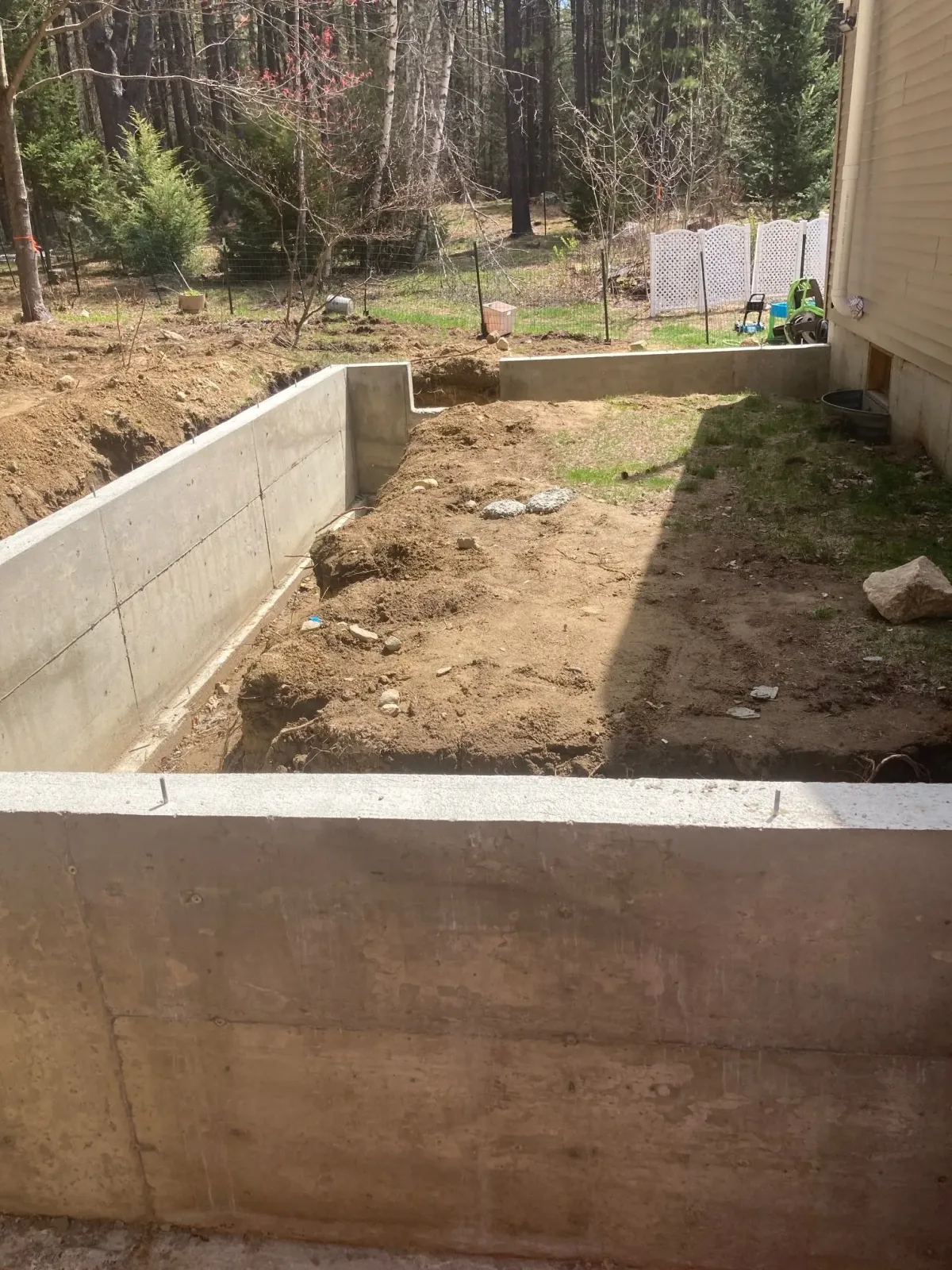 A concrete wall is being built in the backyard of a house.