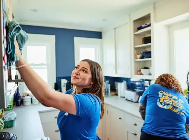 Pristine cleaning team wiping kitchen cabinets and counters