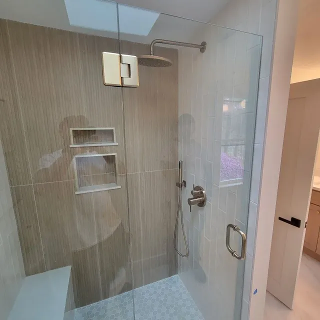 A shower with a glass door and a shower head.