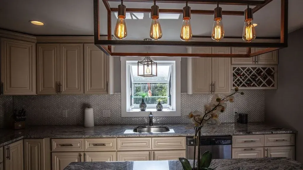 A kitchen with white cabinets , granite counter tops , a sink and a window.