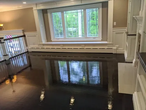 Room with large window reflected on dark, wet-looking floor