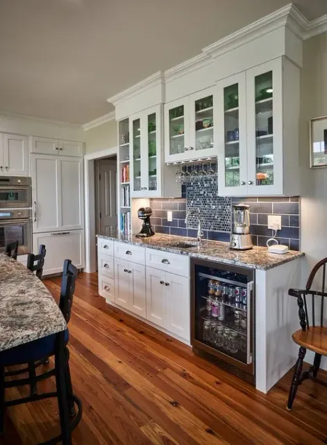 A kitchen with white cabinets , granite counter tops , a refrigerator and a dishwasher.