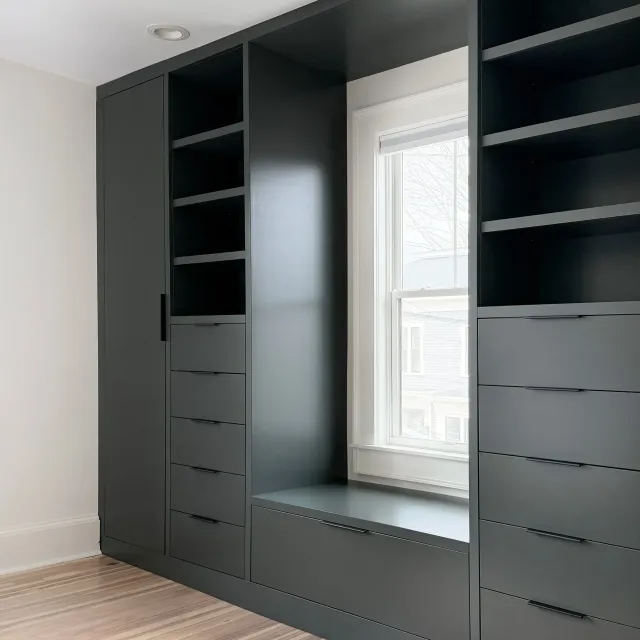 Custom built-in bedroom storage with drawers, shelving, and hanging space in an older Newburyport home.