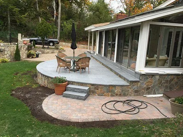A patio with a table and chairs and an umbrella in front of a house.