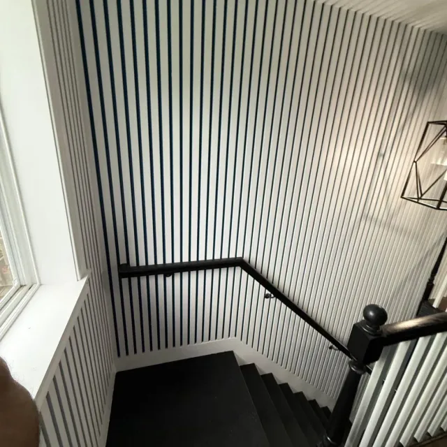 White and navy slat accent wall on stair landing in Winchester, MA — interior carpentry by Tinbercraft Construction